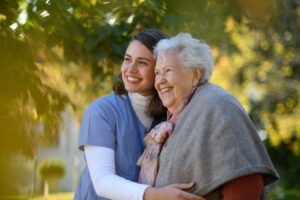 The Gardens of Amarillo | Smiling senior woman embraced by caregiver